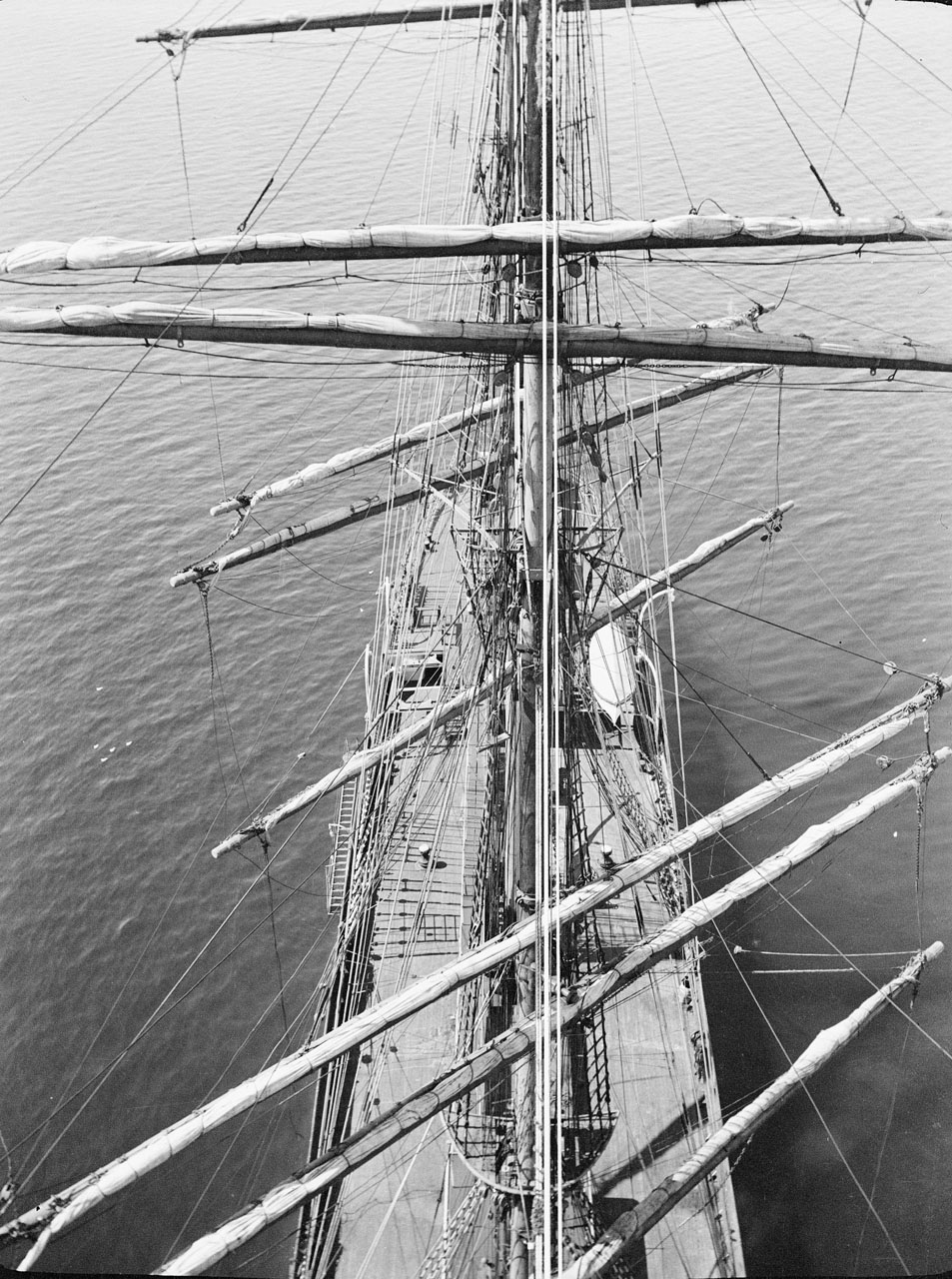 Vue vers la proue depuis la mâture sur le ‘Parma’, au mouillage. Alan Villiers, 1932-33. Le travail de Villiers décrit de façon vivante la période du début du XXe siècle pendant laquelle les voiliers de la marine marchande ou “grands navires” furent en rapide déclin.
